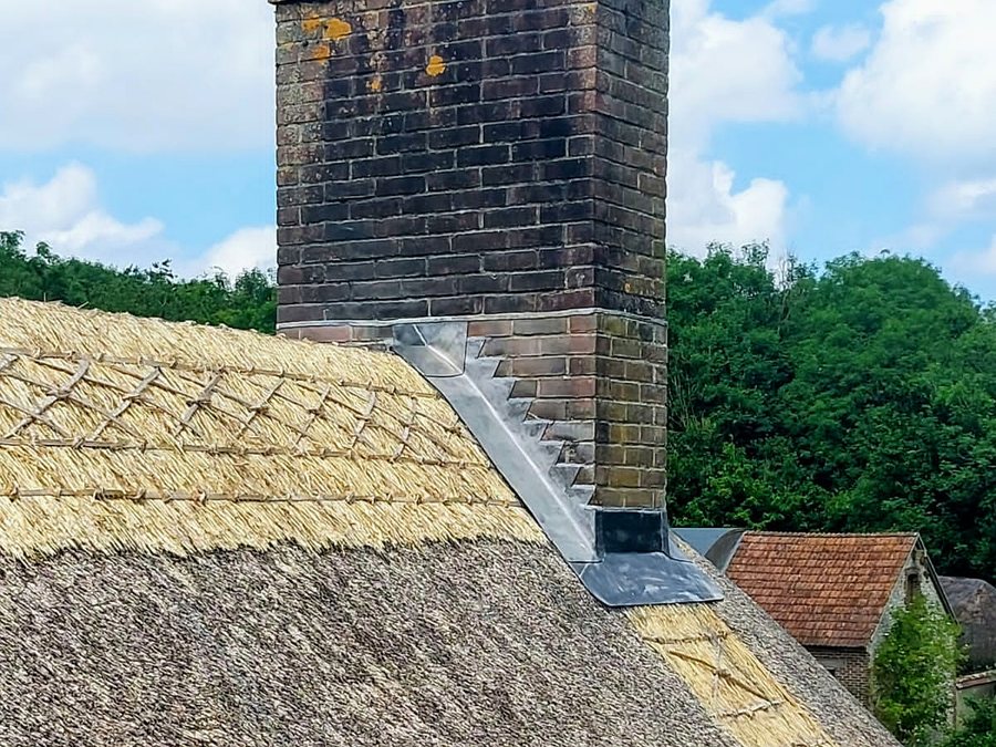 Lead flashing and soakers dressed into a brick stack on a thatched property