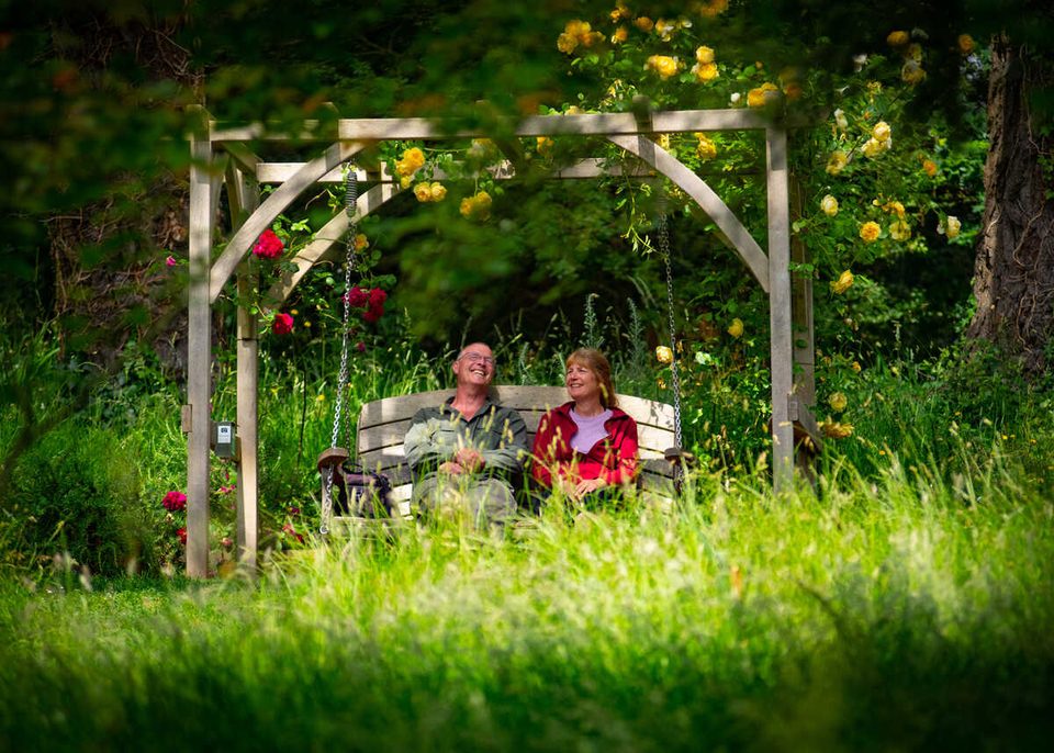 Two visitors sitting on wooden swing seat at Abbotsbury Subtropical Gardens